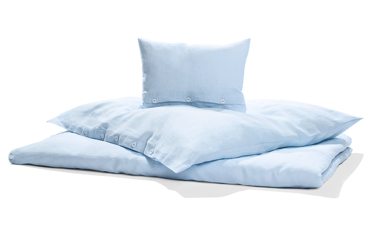 Hochwertige hellblaue Leinenbettwäsche im vorgewaschenen Look, bestehend aus Kissen und Bettbezug mit klassischer Knopfleiste. Natürlich weicher Stoff aus italienischer Weberei, perfekt für alle Jahreszeiten.