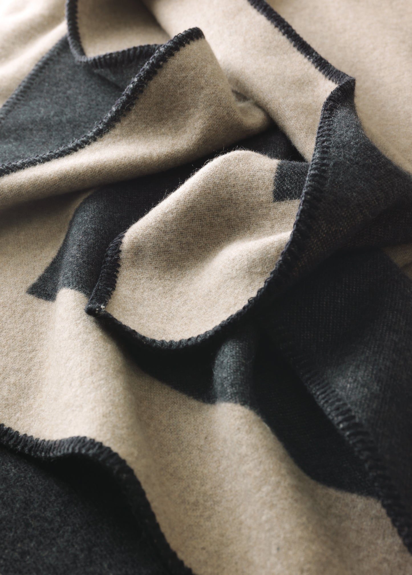 Luxuriöse FRANZ BARTH Kaschmir-Wendedecke Bergamo in elegantem Beige und Anthrazit/schwarz, handgefertigt in Bayern. Zeitloses Design mit weichen Falten und hochwertiger Verarbeitung zeigt die charakteristische Struktur dieser Premium-Wohndecke.