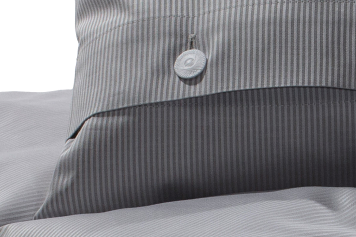 Bettwäsche Castello Feinstreifen Damast: Elegante Kissenbezug-Detailaufnahme in hellgrauem Feinstreifen-Design mit weißem Knopfverschluss, hochwertige Damast-Qualität aus Italien, pflegeleicht und bei 60 Grad waschbar.