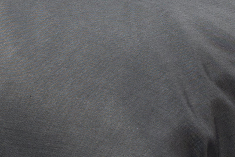 Elegante anthrazitfarbene Bettwäsche aus hochwertiger Damast-Qualität mit weißem Kettfaden in Satinbindung. Nahaufnahme zeigt die feine Melierung und edle Strukturoberfläche des Stoffes.