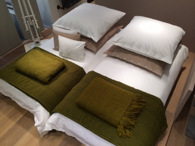 Bettwäsche Bianco Gewaschene Baumwolle: Stilvolles Doppelbett mit weißer Bettwäsche aus gewaschener Baumwolle, dekoriert mit olivgrünen Wurfdecken und Kissen. Holzrahmen-Bett auf Parkettboden, harmonische Kombination aus Naturfarben und modernem Design.