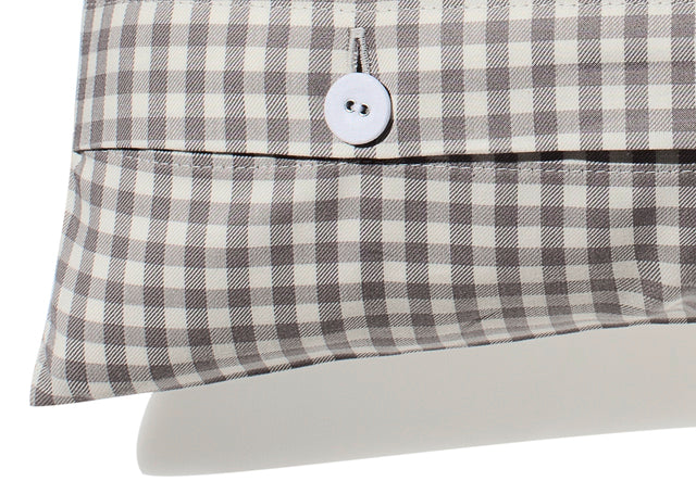 Bettwäsche Vichy 5mm Hamburger Himmelgrau: Nahaufnahme der hochwertigen Knopfleiste mit weißem Stoffknopf auf kariertem Baumwollstoff in Frostgrau und Flüsterweiß. Die 5mm Vichy-Karos zeigen die präzise Verarbeitung und klassische Eleganz der Bettwäsche.