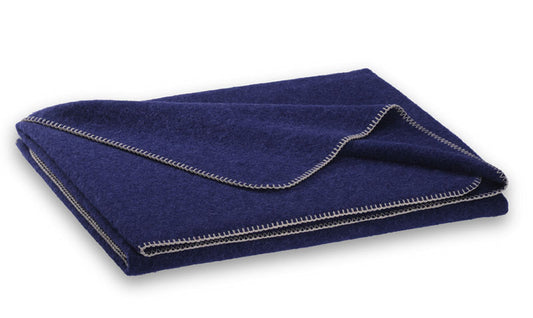 Steiner1888 Wolldecke Alina Heidelbeere - Hochwertige Decke in elegantem Dunkelblau mit kontrastierender weisser Ziernaht, gefertigt aus Alpaka- und Merinowolle. Die gefaltete Decke zeigt ihre luxuriose Textur und klassische Verarbeitung. Wolldecken, Hersteller: Steiner 1888