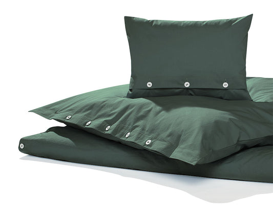 Bettwäsche Bistro Gewaschene Baumwolle in elegantem Dunkelgrün mit Knopfverschluss, aus hochwertigem vorgewaschenem Baumwollperkal. Moderne Bettwäsche mit lässiger Knitteroptik und weichem Griff zeigt gestapelte Kissen und Bettdecke in stilvoller Präsentation.