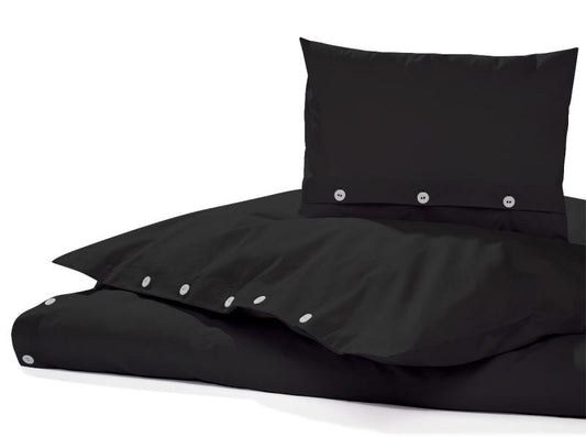 Bettwäsche Corvo Schwarz Gewaschene Baumwolle: Elegante schwarze Bettwäsche aus gewaschenem Baumwollstoff, mit silbernen Knöpfen versehen. Nahaufnahme zeigt die charakteristische leicht gekräuselte Struktur und weiche Textur der Bettwäsche auf weißem Hintergrund.