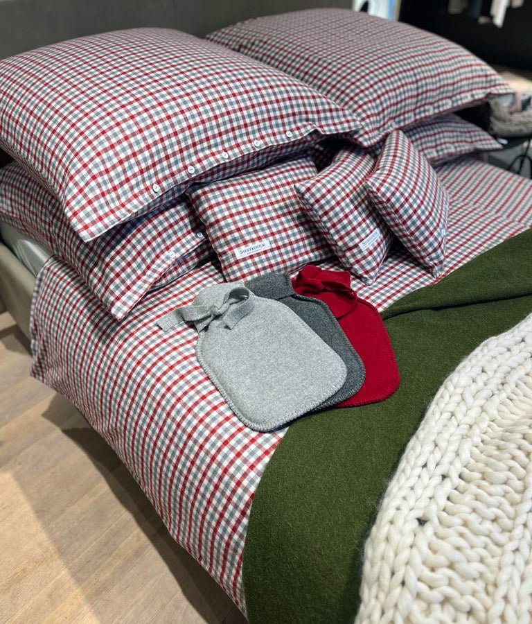 Bettwäsche Klassisches Karo Flanell Rot: Hochwertige Bettwäsche aus reiner Baumwolle im klassischen rot-weißen Karomuster, gestapelte Kissen mit Knopfleiste, dekoriert mit Wärmflaschen in Grau und Rot auf grüner Decke und weißem Stricküberwurf. Alle Bettwäschen, Karierte und gestreifte Bettwäsche, Aktuelle Kollektionen, Stoffkontor.