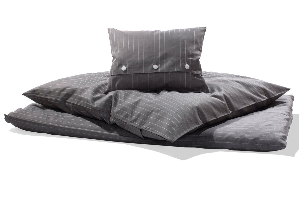 Bettwäsche Caviar Nadelstreifen Damast: Elegante Bettwäsche-Garnitur in grau mit feinen weißen Nadelstreifen, hochwertig verarbeitet mit Knopfleiste. Kissen und Bettdeckenbezug in harmonischer Anordnung präsentiert. Damast-Qualität mit satinierter Oberfläche für höchsten Schlafkomfort.