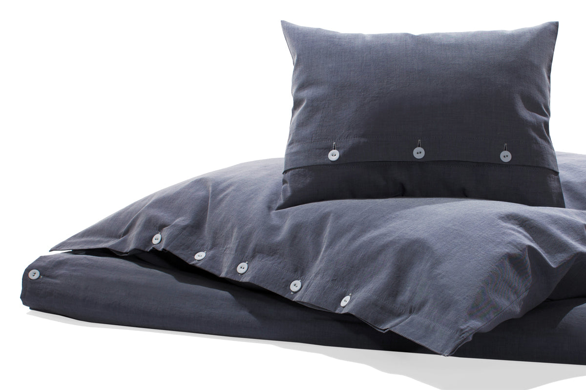 Bettwäsche Bluette Damast: Hochwertige Bettwäsche in kraftvollem Blau mit eleganter Damastbindung, verdeckter Knopfleiste und weißen Kettfäden. Kissen und Bettdeckenbezug in moderner Ausführung auf weißem Hintergrund fotografiert.