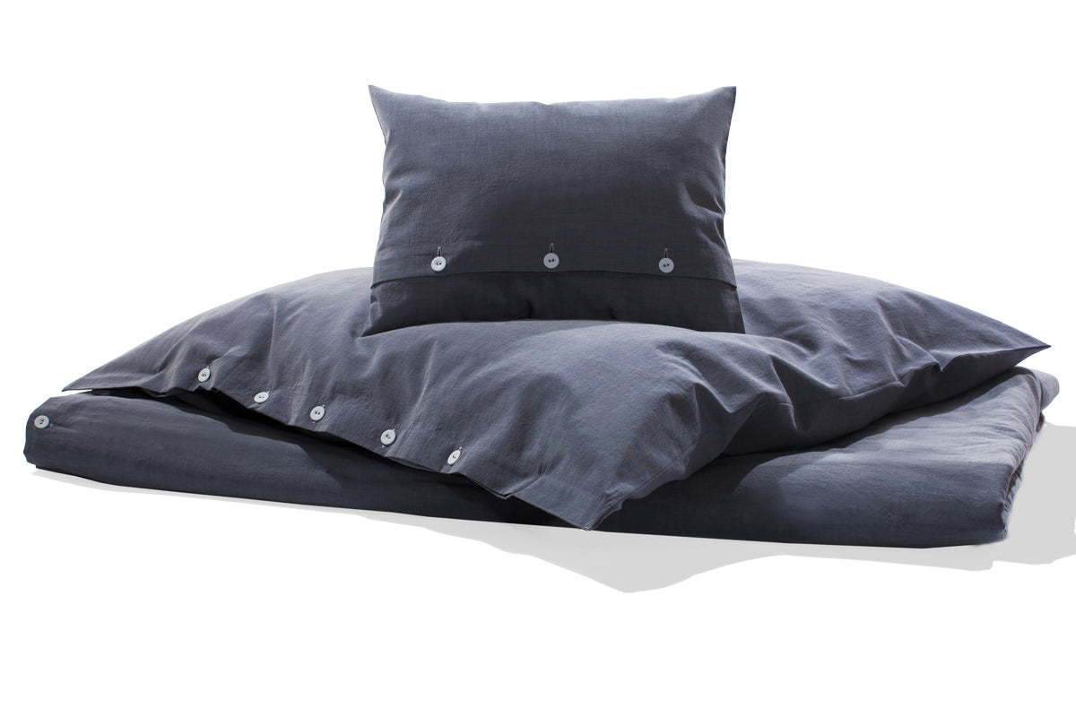 Bettwäsche Bluette Damast: Hochwertige Bettwäsche-Garnitur in kraftvollem Blau mit weißem Kettfaden, elegant verarbeitet mit verdeckter Knopfleiste. Exklusives italienisches Damastgewebe in Satinbindung, bestehend aus Bettbezug und Kissenbezug auf weißem Hintergrund.