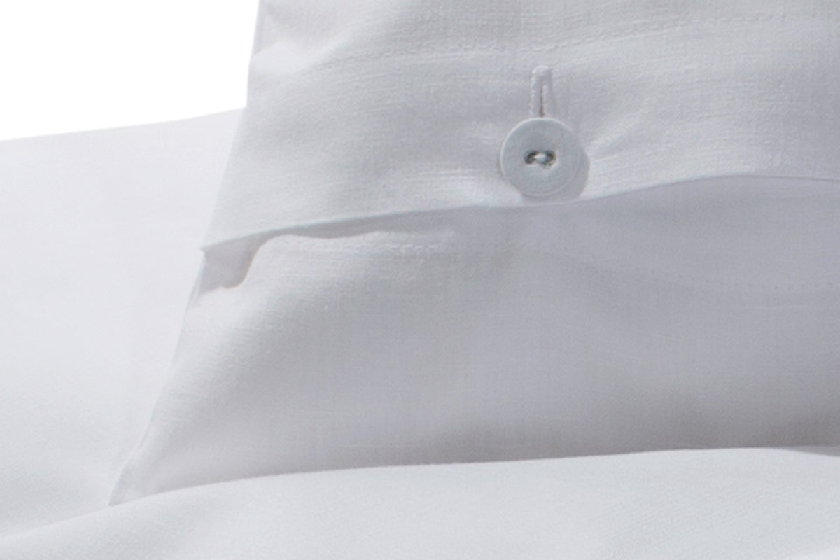 Bettwäsche Halbleinen Weiß: Nahaufnahme einer hochwertigen weißen Bettwäsche aus Halbleinen mit charakteristischer Struktur, gezwirntem Wäscheknopf und klassischer Knopfleiste. Die natürliche Textur und elegante Verarbeitung des Baumwoll-Leinen-Gemischs sind deutlich erkennbar.