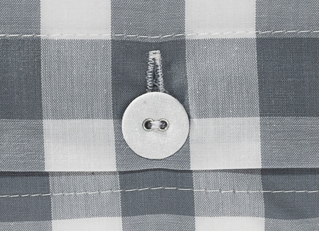 Bettwäsche Nordisch by Nature Klassisches Karo 8 mm Silbergrau - Hochwertiger Knopfverschluss auf kariertem Baumwollstoff in Silbergrau und Weiß. Detailaufnahme zeigt stoffbezogenen Wäscheknopf mit klassischer Knopfleiste und präziser Nahtführung.
