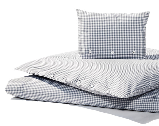 Bettwäsche Nordisch by Nature Vichy Karo Silbergrau: Hochwertige Bettwäsche aus reiner Baumwolle im klassischen Vichy-Karomuster in Silbergrau und Weiss. Der Bezug zeigt traditionelle Stoffknöpfe und eine elegante Knopfleiste. Fotografiert in natürlichem Licht auf weissem Hintergrund.