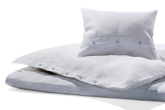 Leinen Bettwäsche in Weiß - Hochwertige weisse Bettwäsche aus reinem Leinen mit klassischer Knopfleiste, in Italien gewebt und in Deutschland gefertigt. Elegante Kissenbezüge und Bettbezug mit hochwertigen Wäscheknöpfen auf hellem, natürlichem Untergrund.