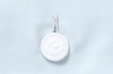 Hochwertiger weißer Wäscheknopf der Bettwäsche Vento Damast, gezwirnt und aufgenäht auf zartem wassergrünem Damastgewebe, charakteristisch für die Premium-Bettwäschenkollektion mit verdeckter Knopfleiste.