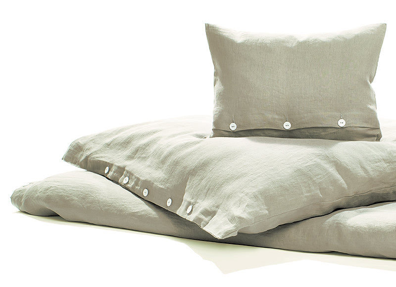 Bettwäsche Reines Leinen Mondstaub - Hochwertige vorgewaschene Leinenbettwäsche in hellem Grau mit beigem Unterton, elegant mit Knopfleiste versehen. Dekorativ drapierte Kissenbezüge und Bettbezug zeigen die natürliche, edle Struktur des italienischen Leinens.