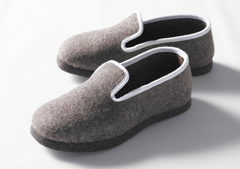 Handgefertigte geschlossene Hausschuhe aus grauem Wollfilz mit weißer Einfassung, dicke Filzsohle für maximalen Komfort. Klassisches Design der Stoffkontor Pantoffeln mit eleganter weißer Bordüre. Hausschuhe geschlossen, Band weiß - Pantoffeln, Hersteller: Stoffkontor