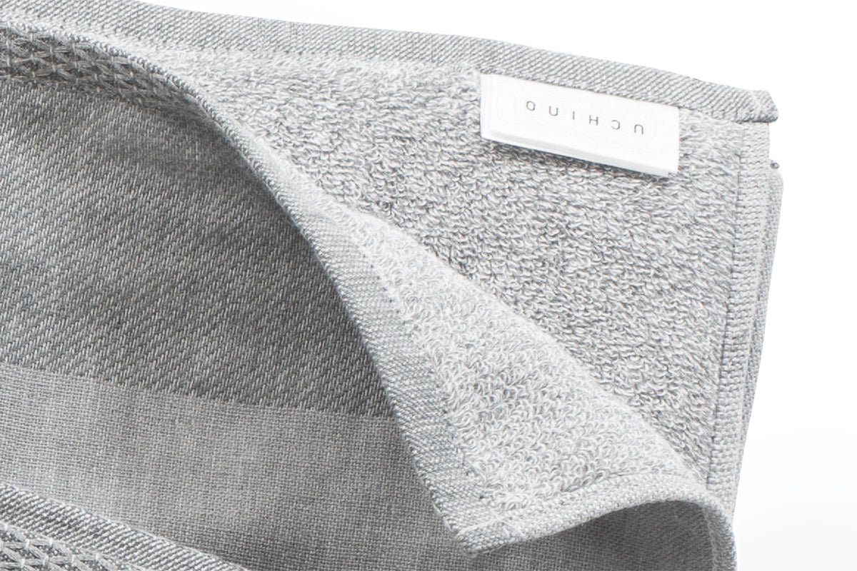 Hochwertiges Handtuch Uchino Zen in Charcoal Grau mit innovativem Doubleface-Gewebe: eine Seite feiner Frottee, andere Seite Gaze-Struktur. Zeigt einzigartige Materialdetails und Uchino-Label. Handtücher, Hersteller: Uchino