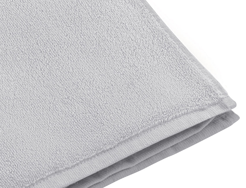 Handtuch Dreampure Weseta Silver: Hochwertiges silbergraues Baumwollhandtuch mit gefalteter Ecke, zeigt feine Webstruktur und eleganten Saum. Luxuriöses Frotteetuch aus nachhaltiger Schweizer Produktion. Handtücher, Hersteller: Weseta Switzerland.