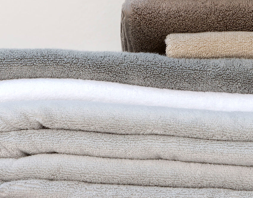 Handtuch Dreampure Weseta Silver: Gestapelte hochwertige Frotteehandtücher in eleganten Grau- und Beigetönen, gefertigt aus 100% Baumwolle. Die weichen, formstabilen Handtücher zeigen eine charakteristische Frotteestruktur und premium Qualität. Handtücher, Hersteller: Weseta Switzerland.