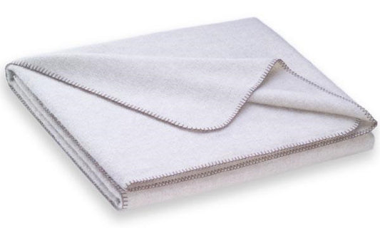 Steiner1888 Wolldecke Nora Perle: Elegante Naturdecke aus 50% Merinowolle und 50% Alpaka in perlfarbenem Ton mit kontrastierender Kanteneinfassung. Die gefaltete Decke zeigt die hochwertige Verarbeitung und weiche Textur. Wolldecken, Hersteller: Steiner 1888
